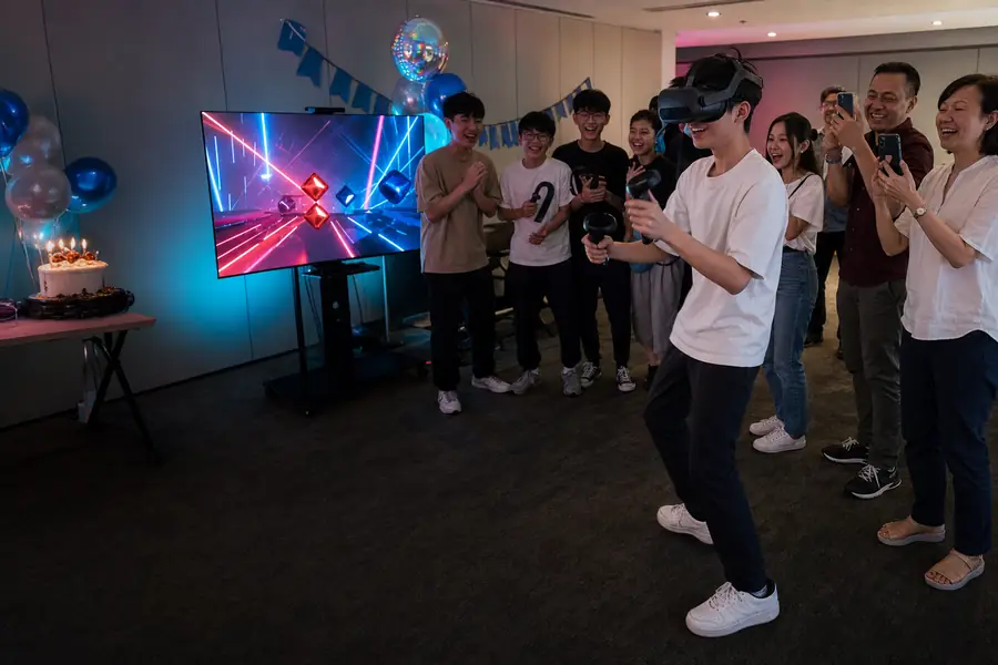 Friends cheer a teenager playing VR at a birthday party