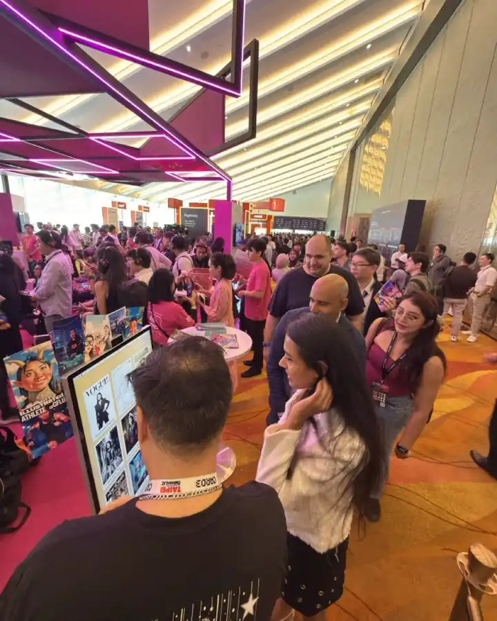 A crowd gathers round the booth on a busy exhibition floor